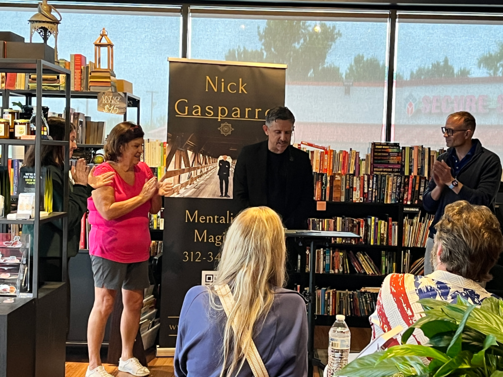 Volunteer and audience applaud during Nick Gasparro's live mentalism performance