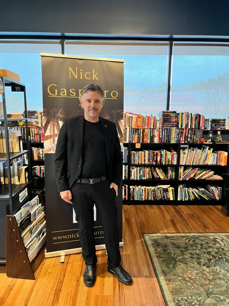 Naperville magician and mentalist Nick Gasparro in front of his banner at a bookstore show
